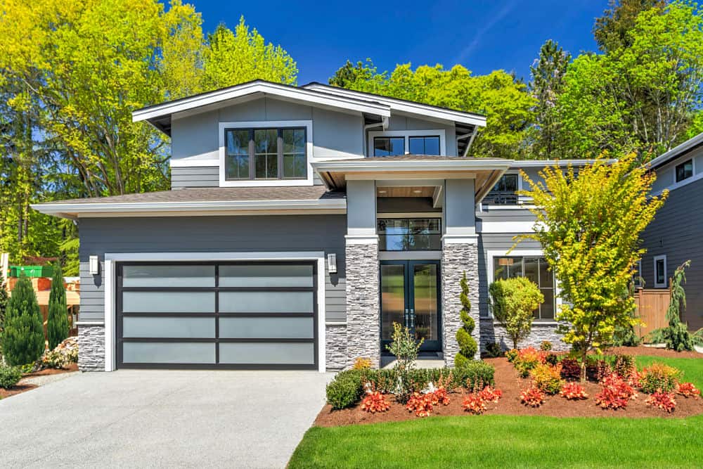 Modern contemporary house exterior with luxury details, landscaping, stone, wood, glass, lots of large windows.
