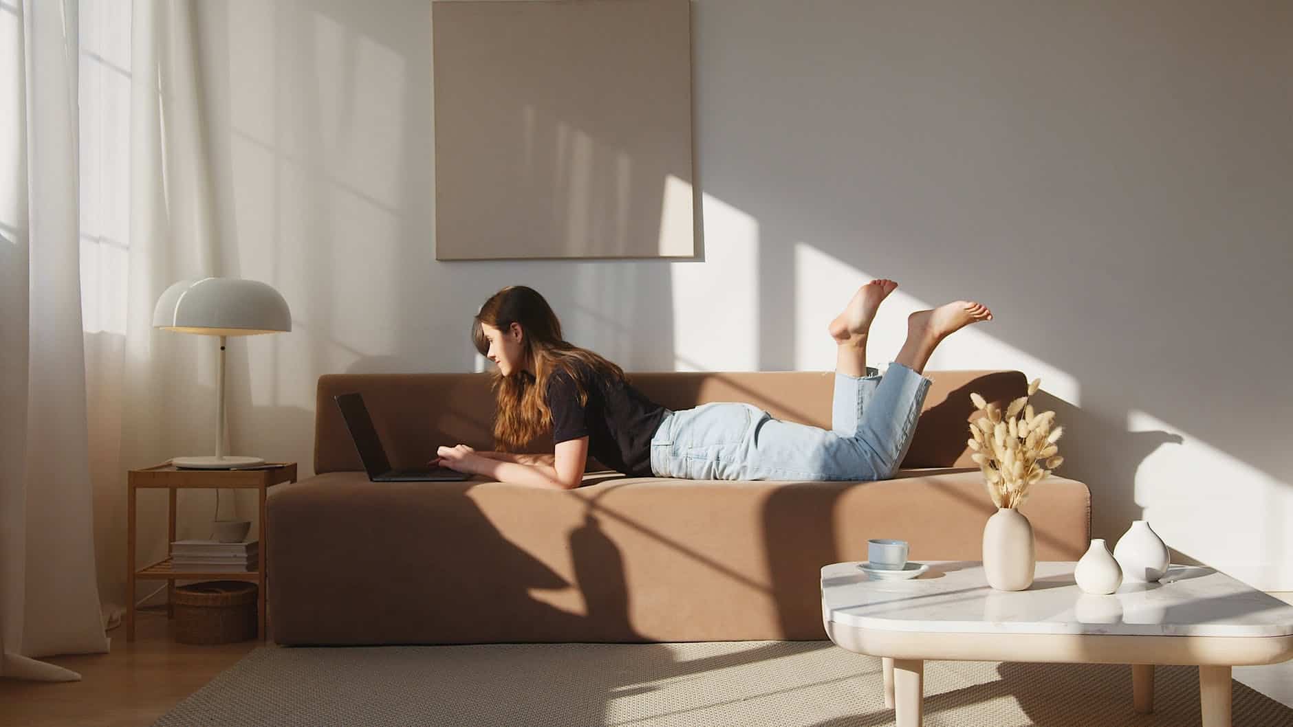 content woman resting on sofa with laptop